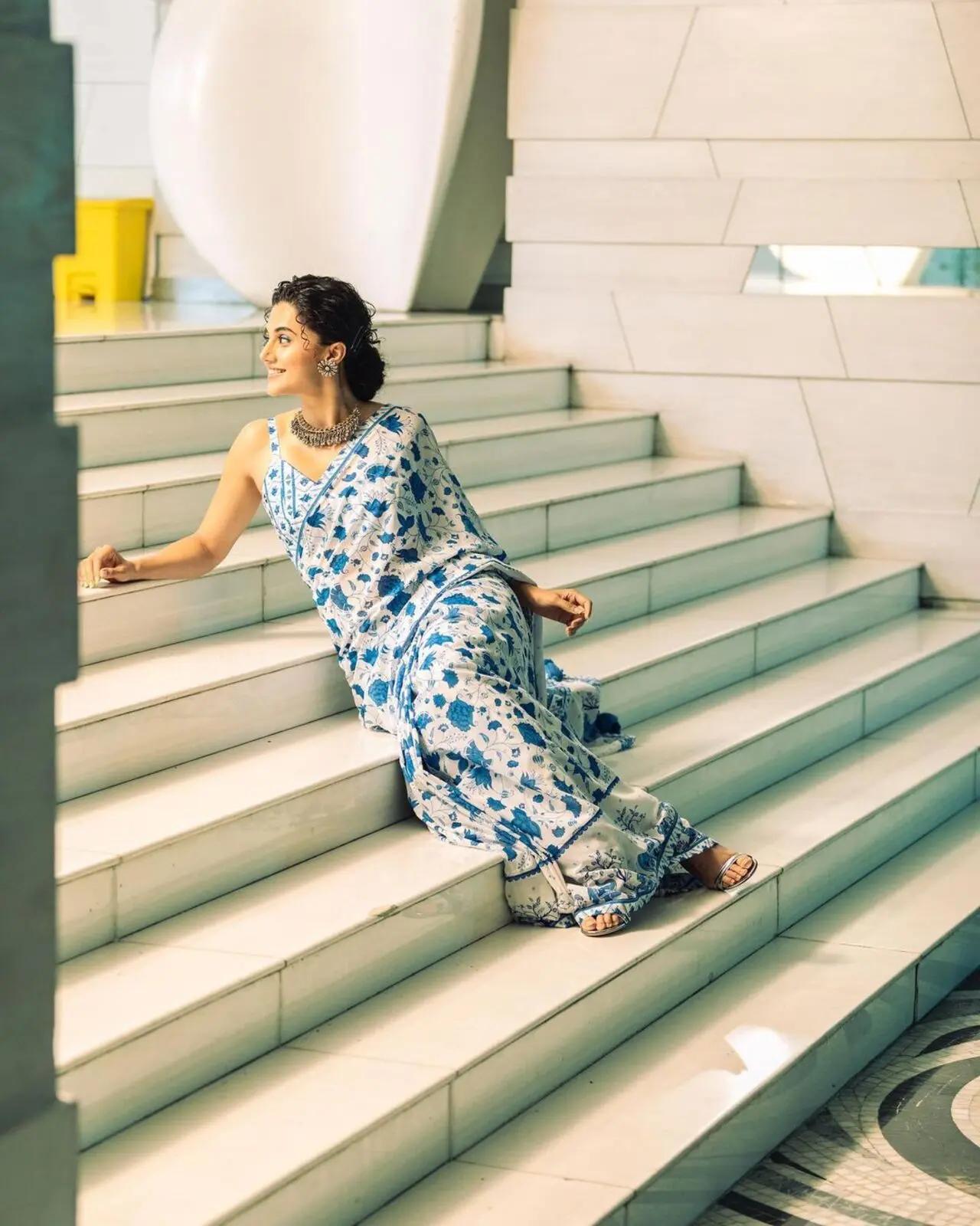 In this look, she is wearing a white saree with blue patterns. The calm and composed colour with a simple background looks refreshing