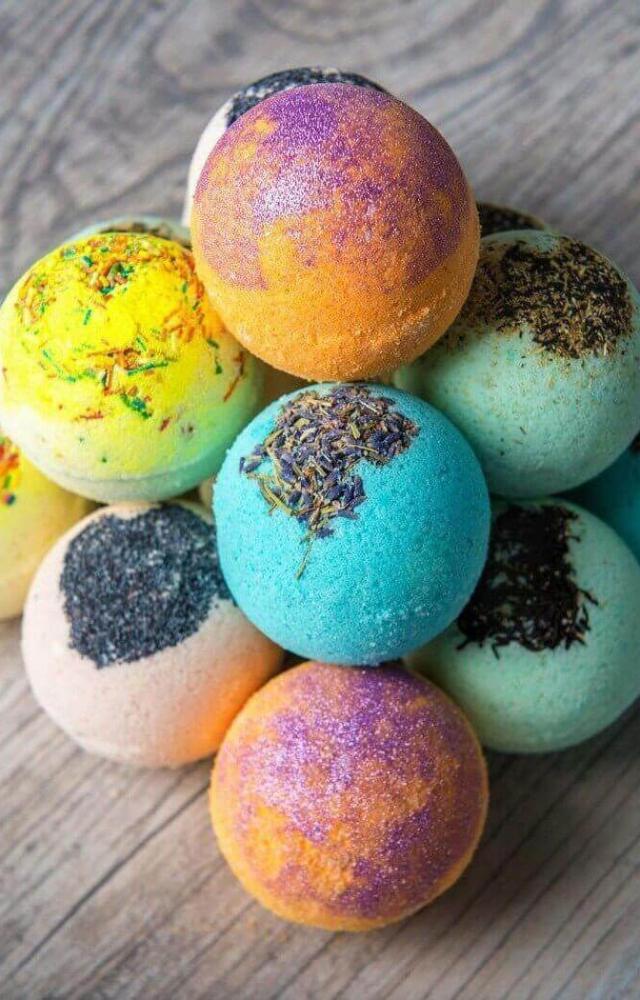 A simple bath bomb recipe includes baking soda, citric acid, cornflour, essential oils, and food colouring. Use fun moulds and wrap them in cellophane.