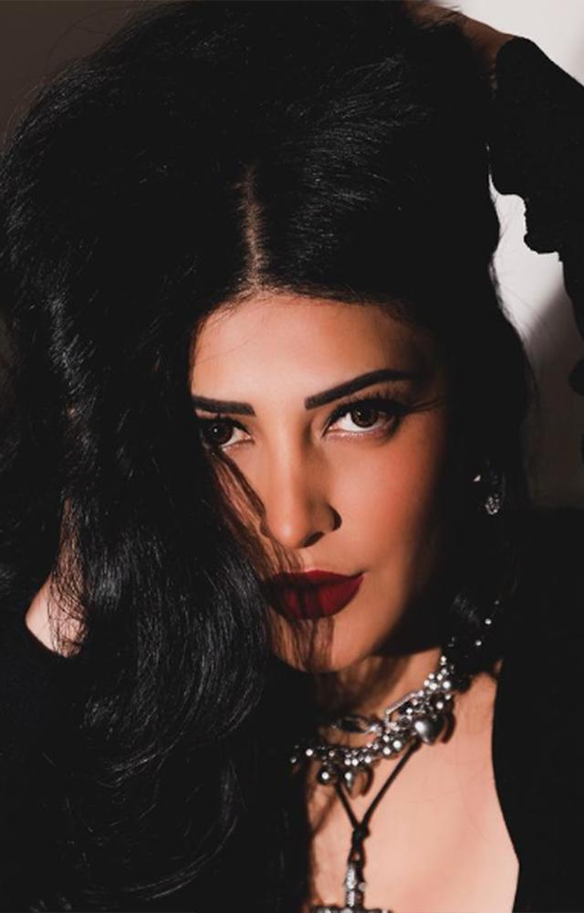 Step into a world of allure as Shruti Hassan radiates heat and sophistication, pairing her deep red matte lipstick with a sleek black dress