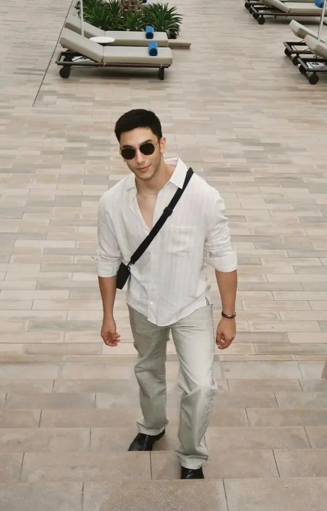 Embracing summer vibes, Vedang Raina looks fresh and breezy in a white cotton shirt and light-toned pants, accessorized with a cross-body bag and sunglasses