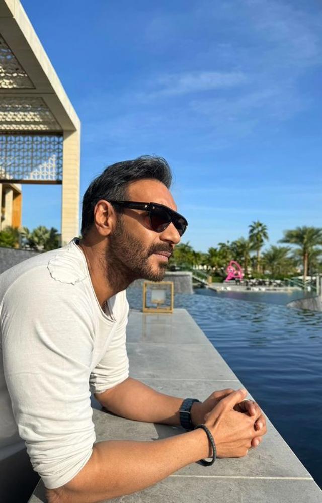 Ajay Devgan strikes a pose in stylish black shades, oozing charisma.