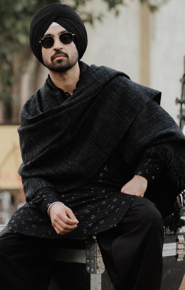 Diljit Dosanjh enters the scene wearing a sleek black suit that epitomises elegance and radiating pure charisma and classic style.