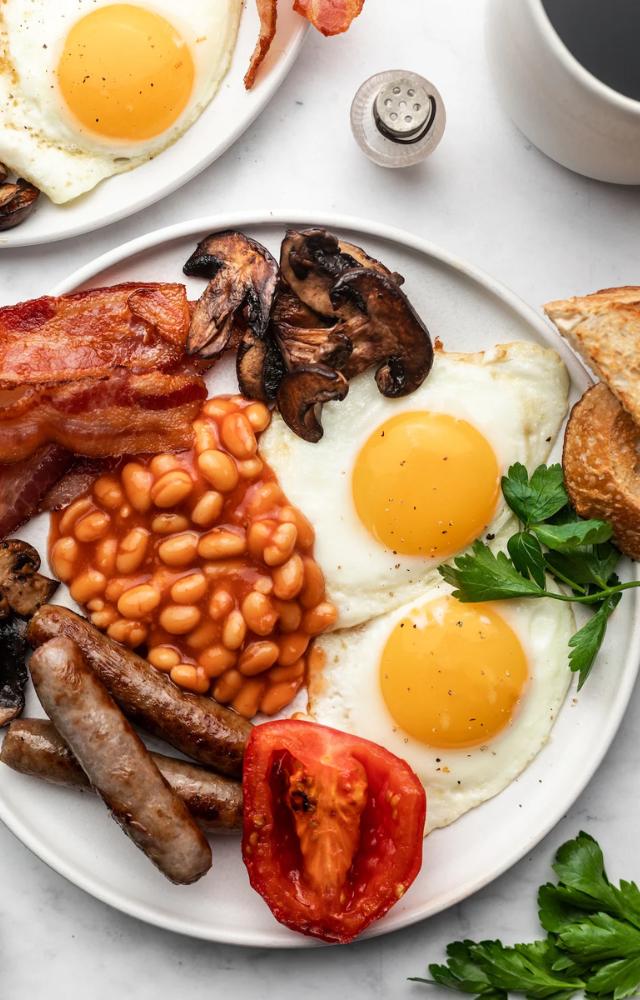 A hearty spread featuring eggs, sausages, bacon, beans, and toast is a satisfying choice.