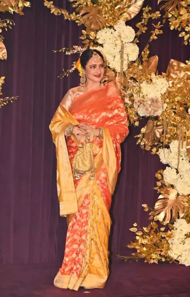 Rekha stunned in her orange-colored saree, exuding timeless elegance.