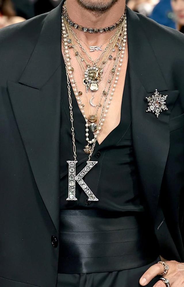 SRK’s look was accentuated with layered talismanic chains, a crystal-studded ‘K’ pendant, and a diamond star brooch, adding depth and meaning.