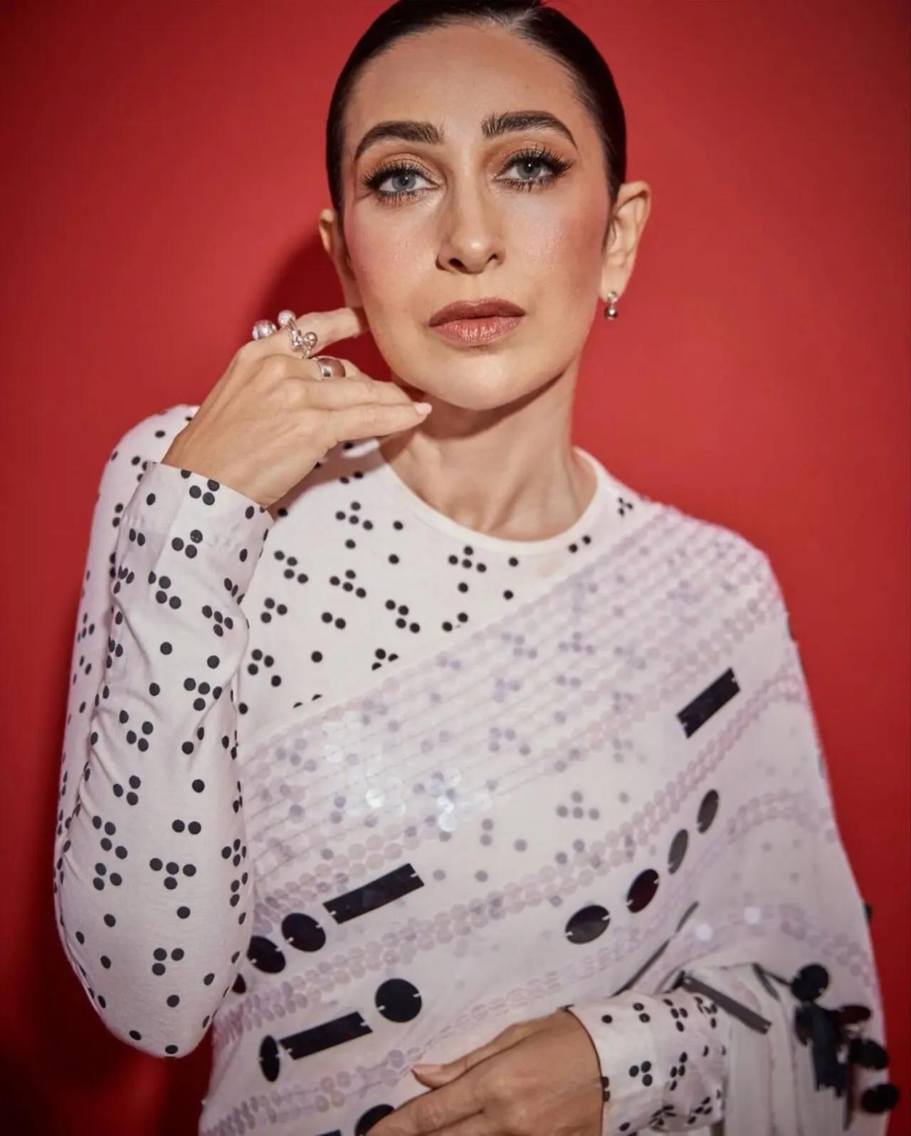 Karisma Kapoor, the OG 90s girl, dressed in a striking white saree with black shimmery design on it. She wore the saree with full sleeve blouse