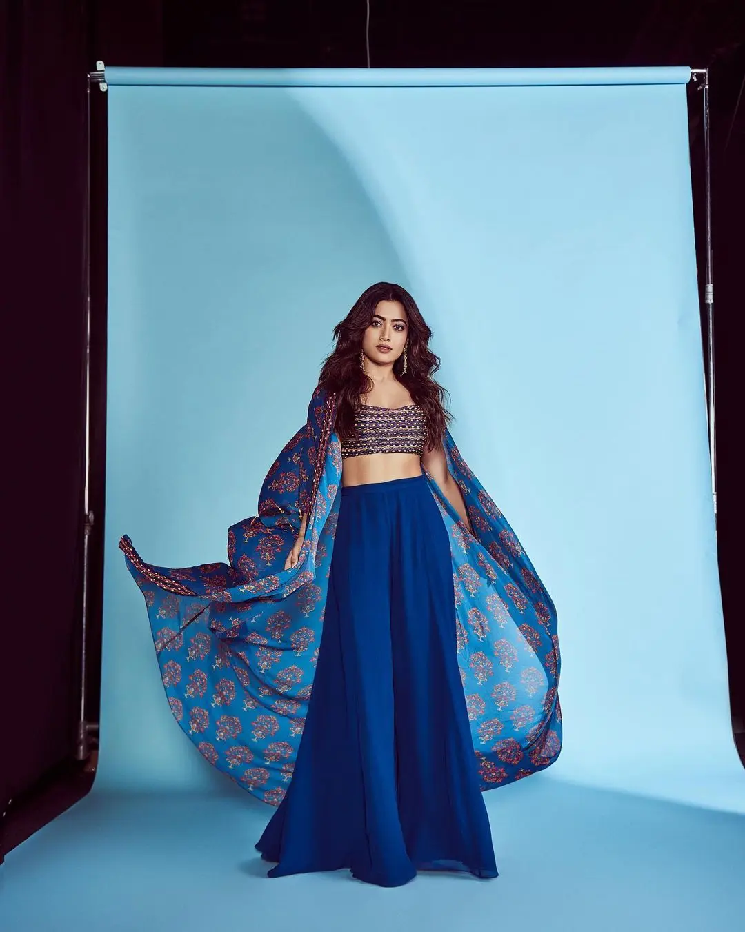 Cut the confusion between Indian and western styles by opting for an Indo-western look. Rashmika paired a blue palazzo with an embroidered crop top and a simple shrug