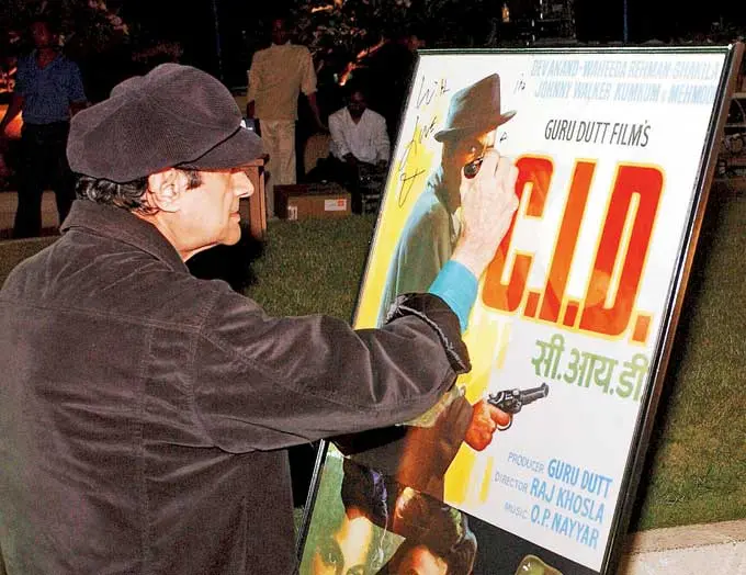 Dev Anand signs a poster of his famous film `CID`. The poster was auctioned at the launch party of the book Bollywood: Popular Indian Cinema at a Bandra hotel. Picture/mid-day archives