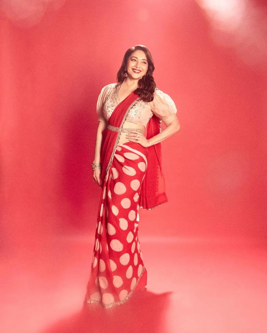 Madhuri Dixit`s outfit for Navratri Day 2 is a stunning red and gold polka dot saree that beautifully captures the essence of elegance and is a perfect pick for the occasion. The breezy drape of the saree strikes a harmonious balance between chic and stylish