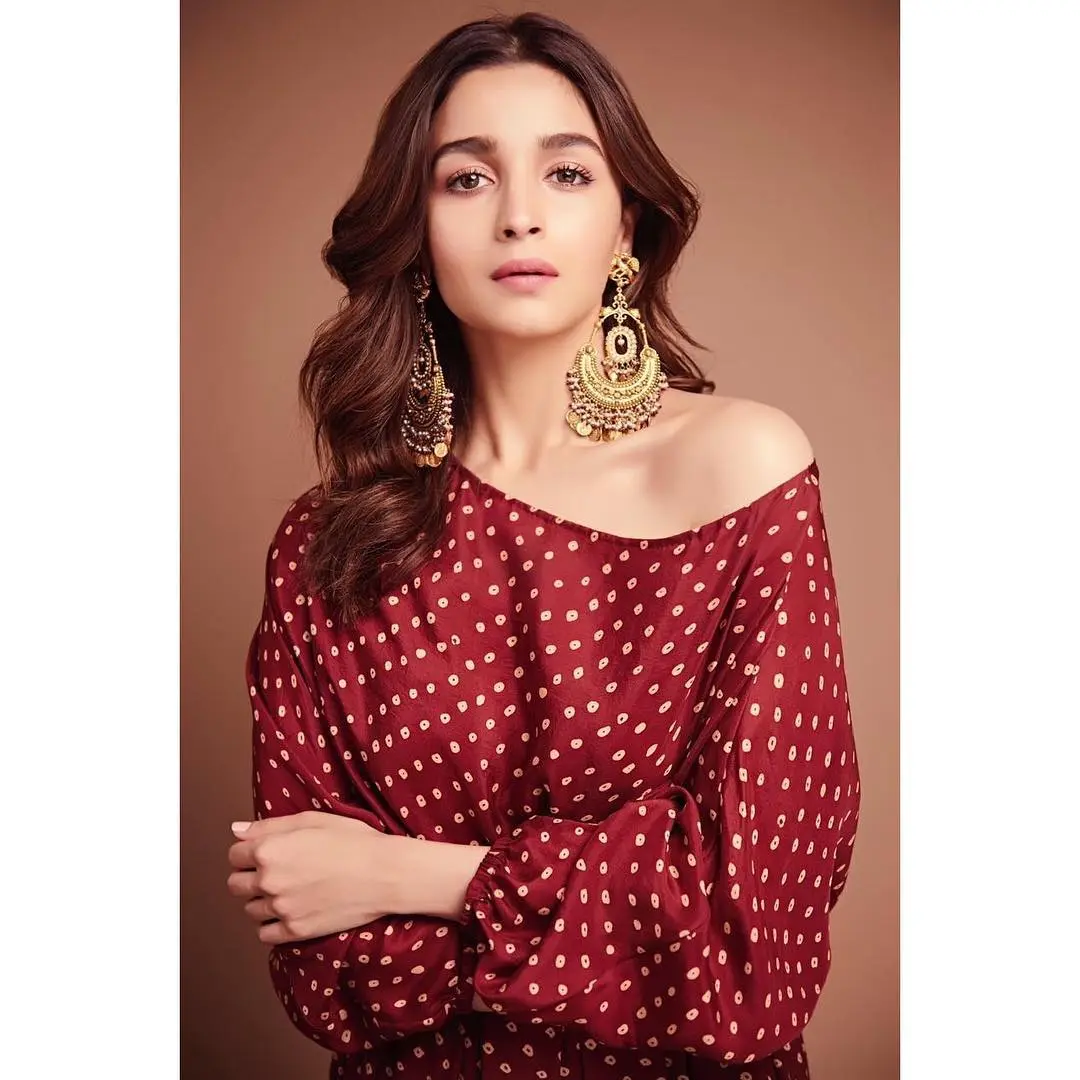 As Navratri enters its third day, Alia Bhatt is our style icon, shining in a maroon one-shoulder gown that exudes elegance. She completes the look with beautiful chandbalis and strappy sandals, striking a perfect balance between traditional and modern.