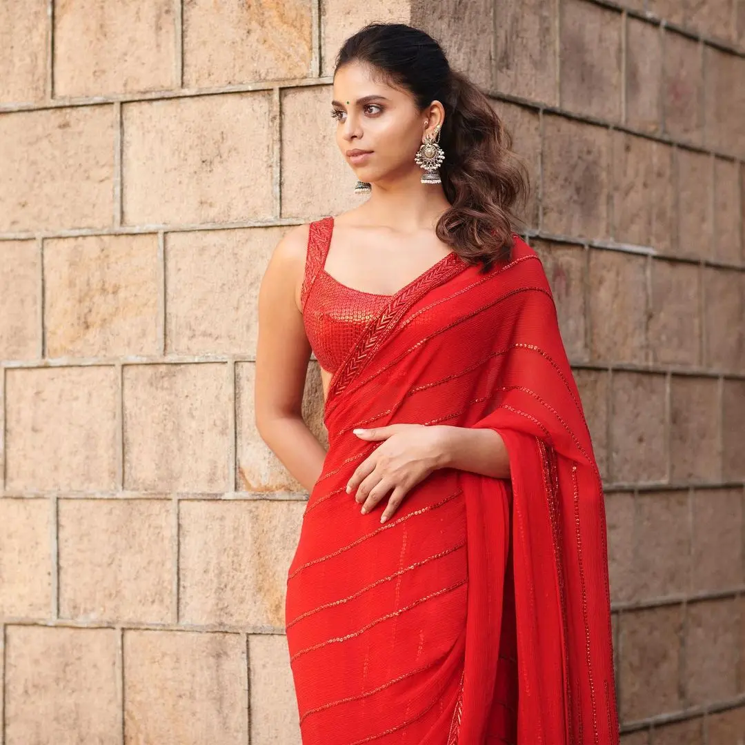 For Navratri Day 2, Suhana Khan`s fashion choice steals the show in a striking red saree paired with a sleeveless blouse, epitomizing the festive spirit. Her untied hair and signature makeup bring out her natural beauty.