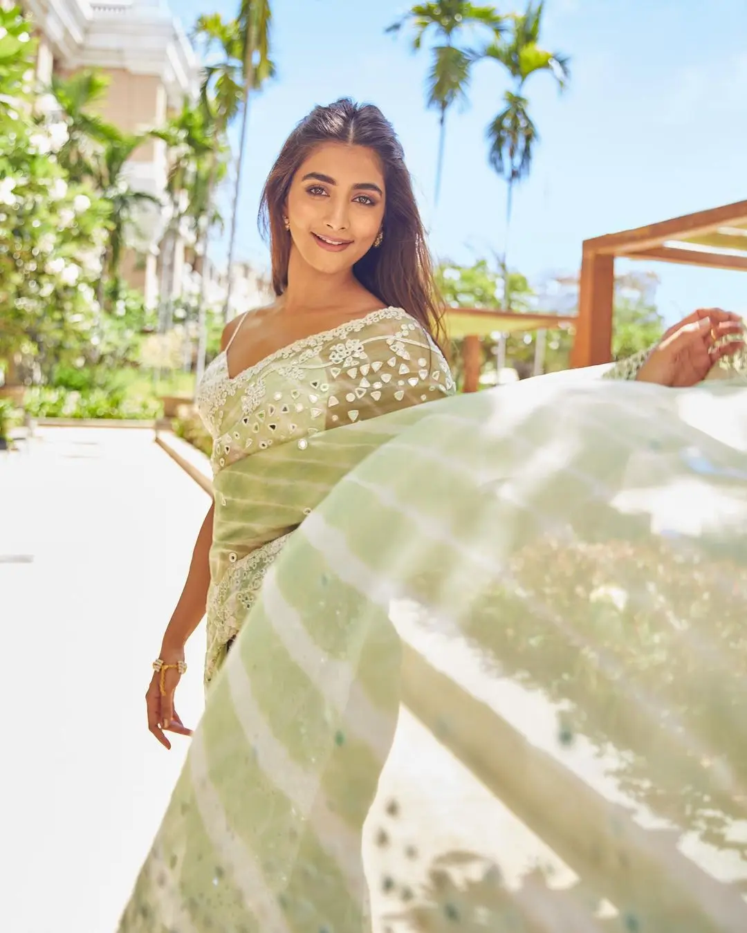 She looked absolutely stunning in a green and white saree, exuding elegance and charm. Her outfit featured subtle mirror work accents, and she paired it with a white strappy blouse that had a stylish plunging neckline.