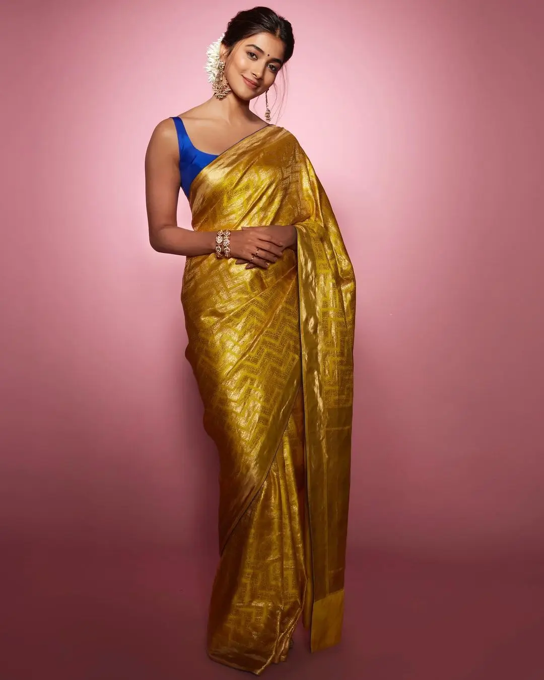 Pooja Hegde looked stunning in a bright yellow sari at a promotional event. Her sari was made from luxurious silk and featured a vibrant sunshine hue. What made it truly stand out was the intricate gold zari work, which gave it a touch of opulence, almost resembling a golden fabric.