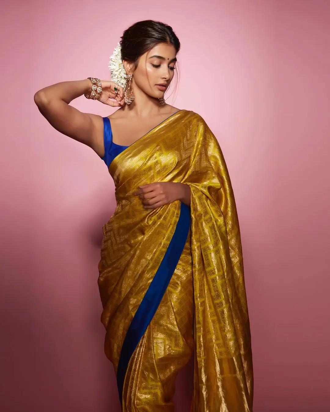 While traditional saris often incorporate classic floral and animal motifs, Hegde`s Raw Mango sari showcased zari work in modern chevron patterns, adding a contemporary twist to the traditional style. To create a striking contrast, she paired it with a sleeveless cobalt blue blouse made from the same fabric, which also featured cord piping on the yellow sari.