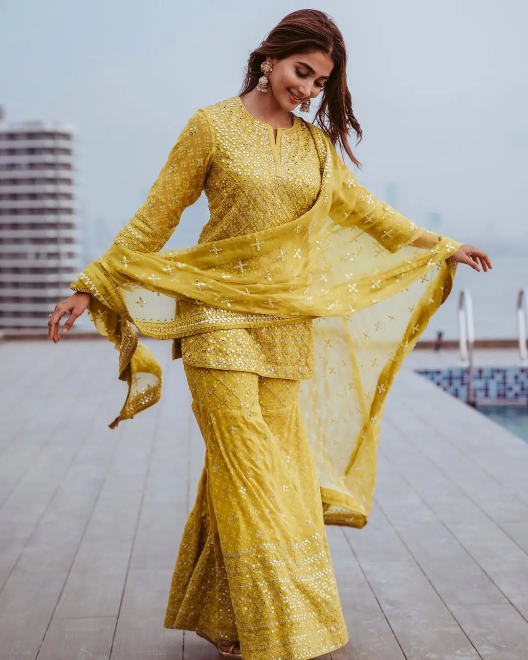 To complete her look, she paired the kurta with yellow sharara pants featuring embroidery in both yellow and silver threads at the ankles. Pooja elevated the festive appeal of her attire with a yellow silk dupatta adorned with yellow thread embroidery and zari work along the borders.