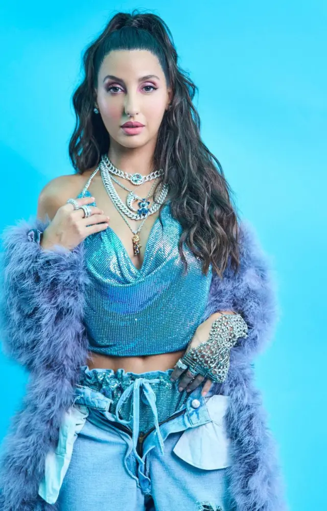 She wears a sequined crop top with matching jeans, adding a furry coat for a flawless finish