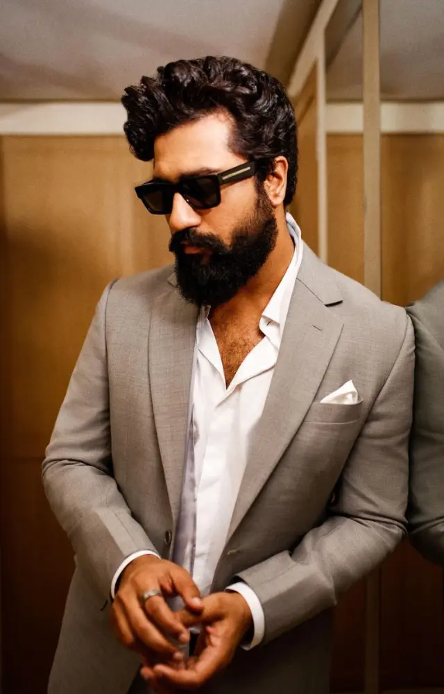 Dressed in a sharp grey suit paired with a crisp white shirt, he exudes sophistication