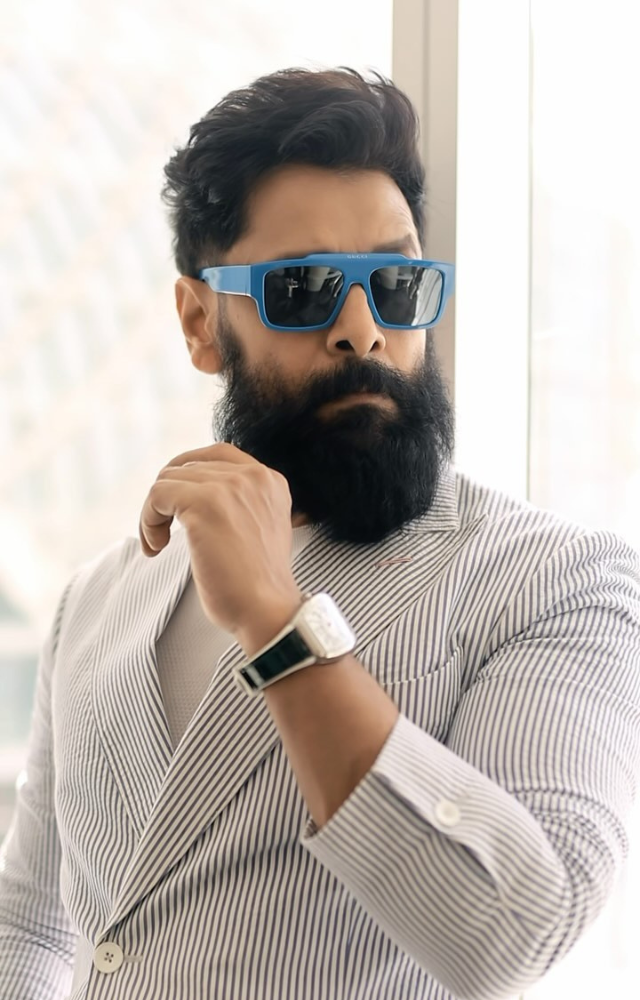 Sporting a crisp white blazer with striped details, paired with blue jeans, he effortlessly blends sophistication with casual cool