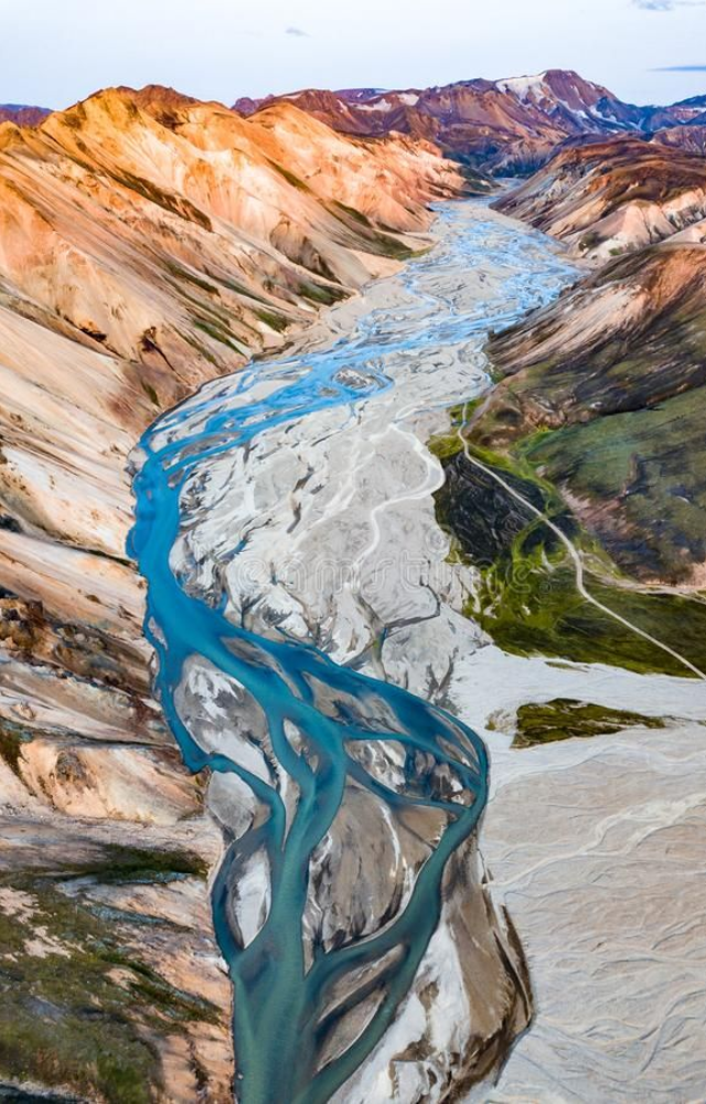 This volcanic region glows with reds, oranges, and greens due to rhyolite rock and geothermal activity beneath the surface.
