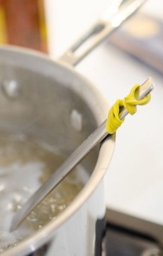 Loop a rubber band at the top of a utensil. It’ll stop the spoon or spatula from sliding into hot pots while cooking or stirring.

