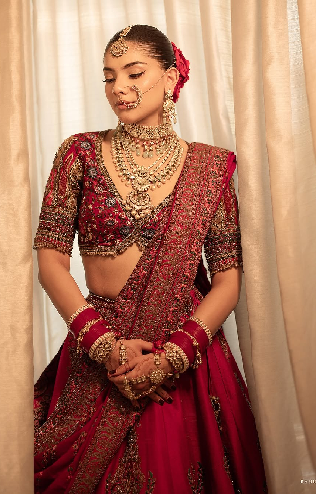 The bride chose a dazzling red lehenga paired with statement gold jewelry. Hridi Narang looked stunning as she finished her look with a neatly tied bun.