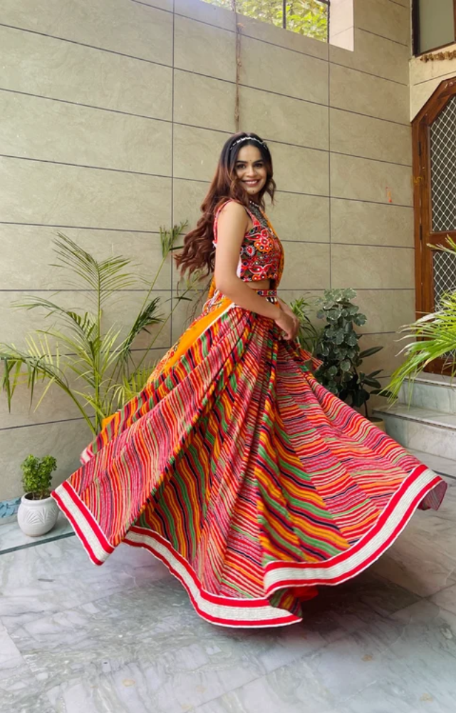 Many women wear flowy skirts with dupattas tied around the waist or draped over the shoulder for Garba, allowing easy movement and adding to the festive look.