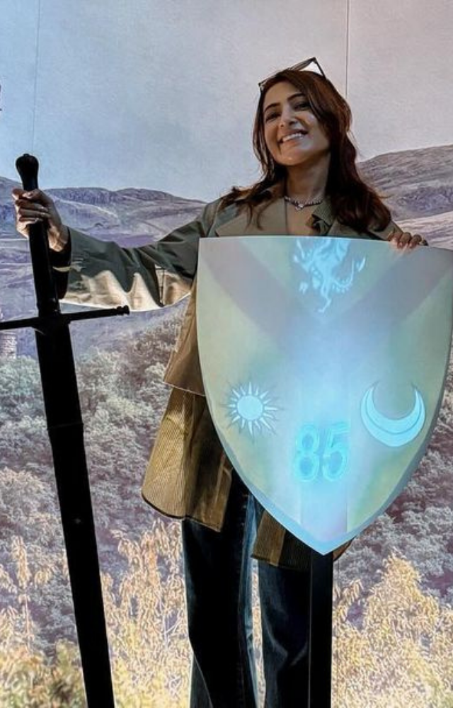 Samantha playfully wields a sword and shield amidst breathtaking countryside sceneries