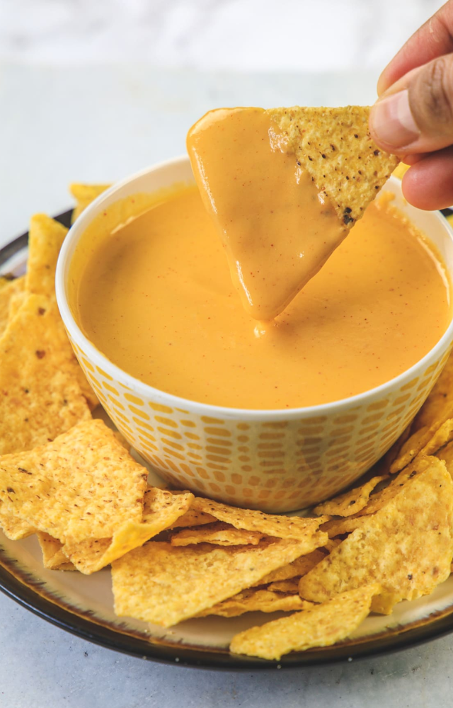 A delicious combination of crispy tortilla chips covered in a gooey, creamy cheese sauce is known as nachos with cheese dip