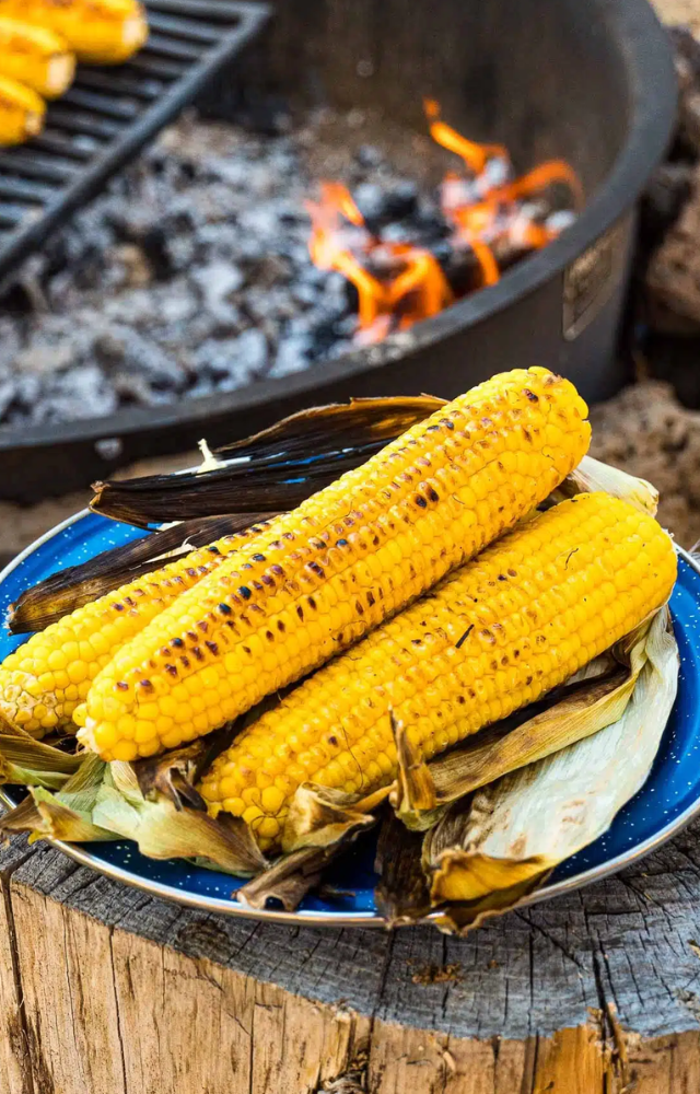 Enjoy the smoky flavor of grilled corn on the cob, brushed with tangy spices and lime juice, a favorite snack during the rainy season.