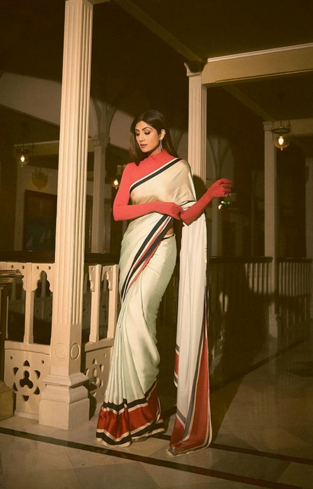 With every elegant step, Shilpa Shetty captivates in a gorgeous red-white saree, radiating brilliant elegance and timeless beauty.