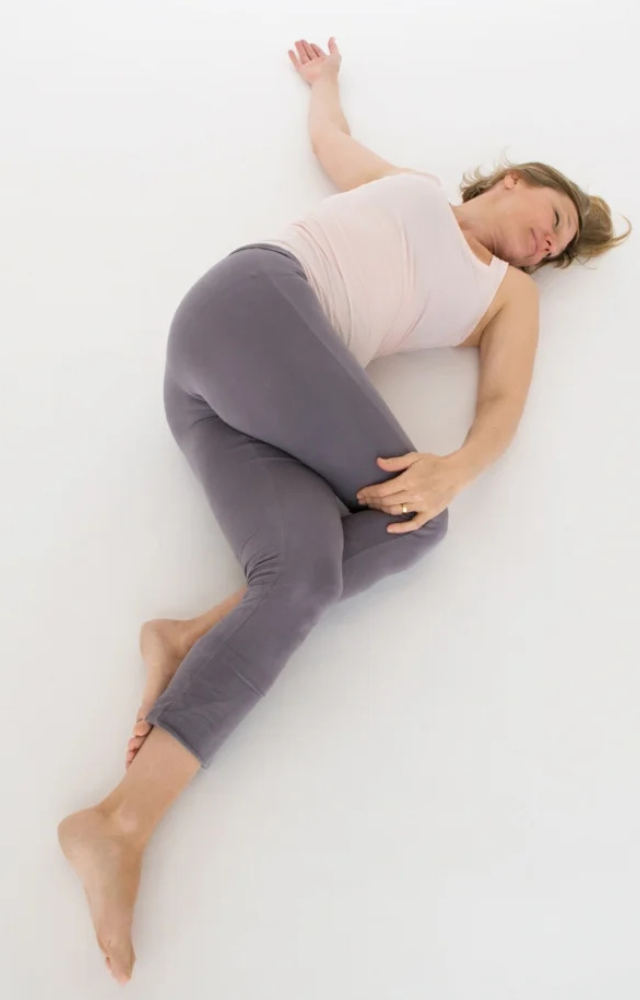 Supine Twist is a healing yoga pose in which you lie on your back and gently twist your spine to release tension in the shoulders and back