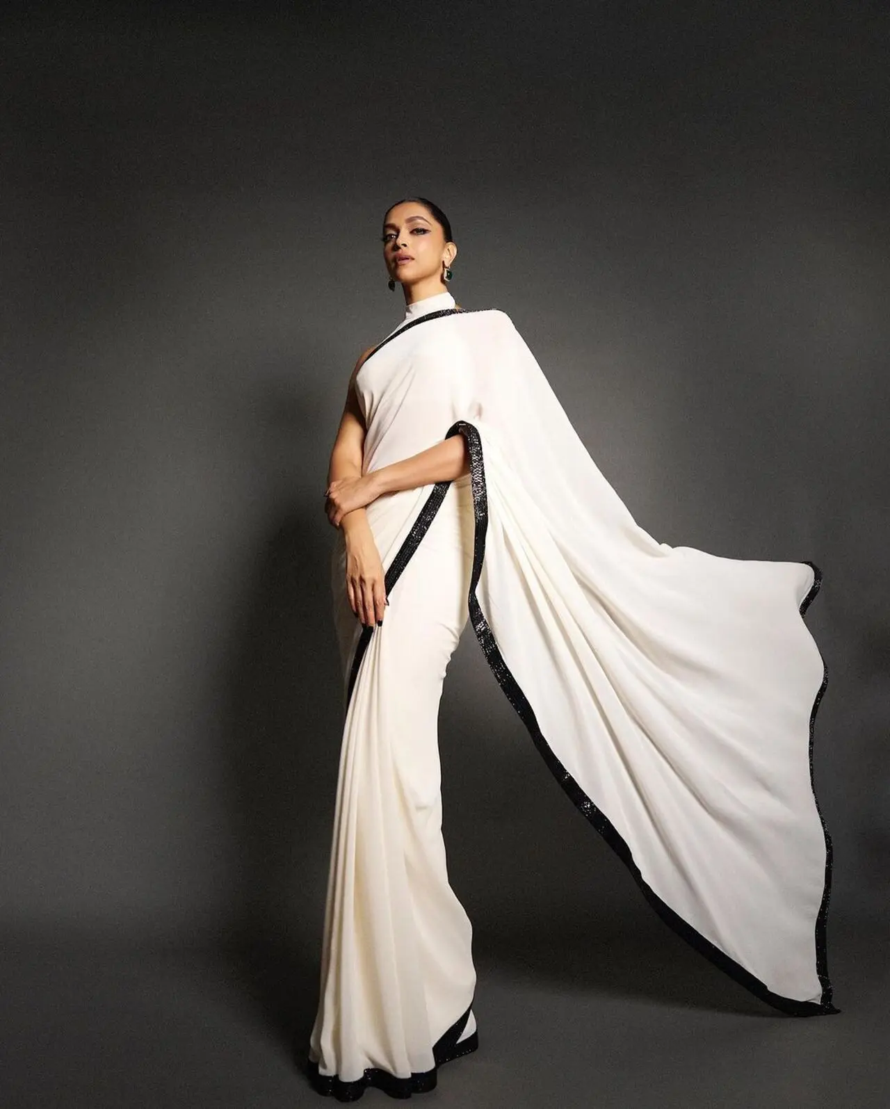 The plain white saree as sequin black border. The actress opted for dramatic eye makeup and green emerald earrings to complete the look